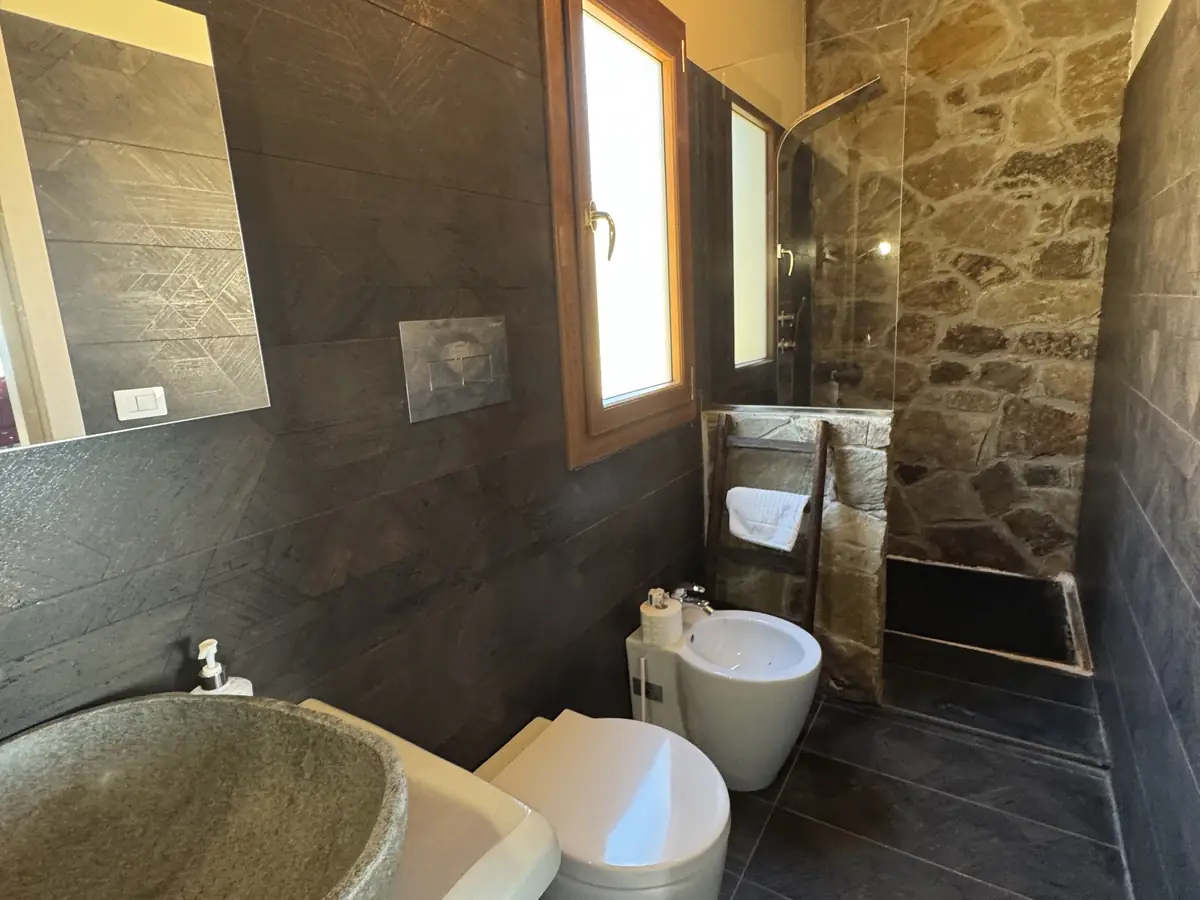 Il bagno in pietra con il lavabo scolpito e la finestra