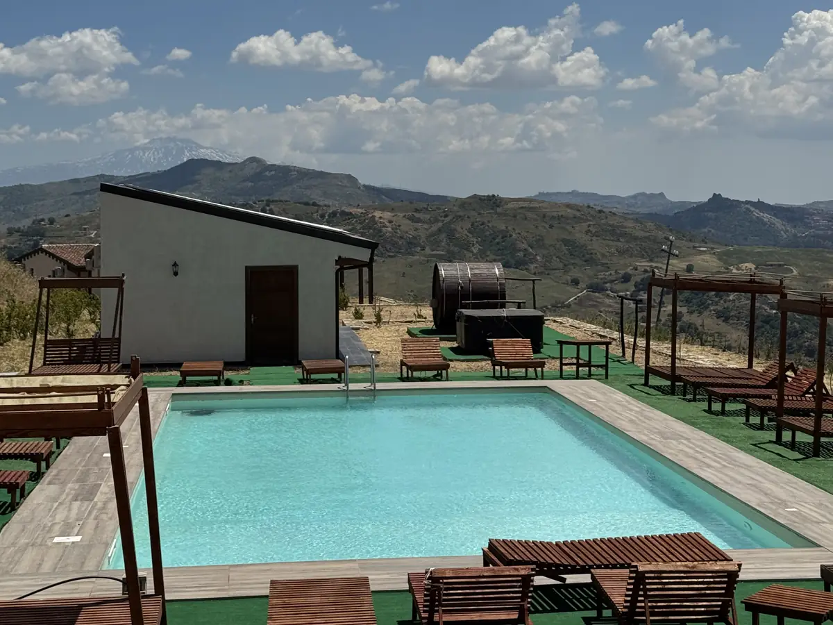La piscina turchese con il bungalow e le colline