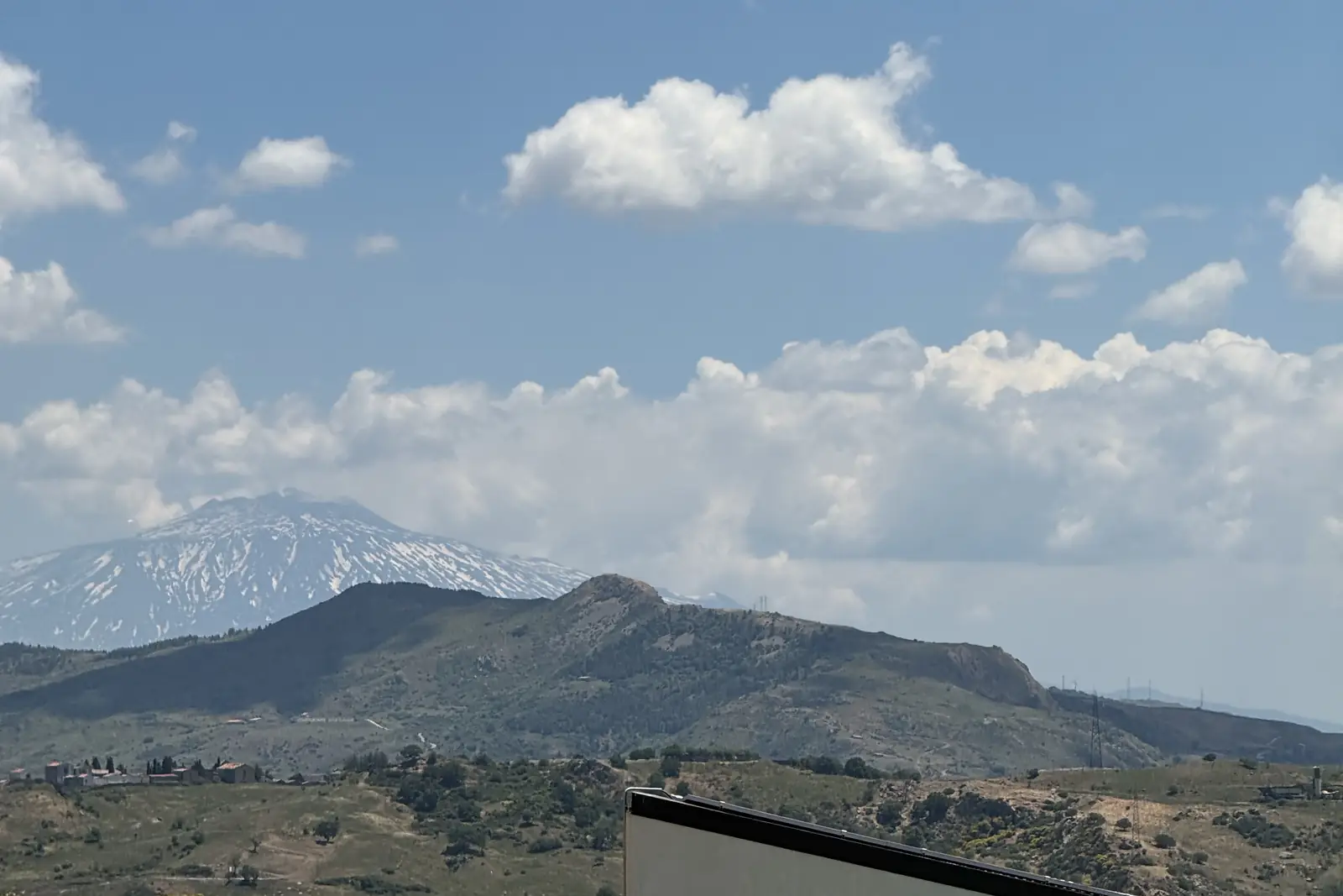 I monti Nebrodi con le nuvole, un bungalow bianco e i lettini dell’agriturismo