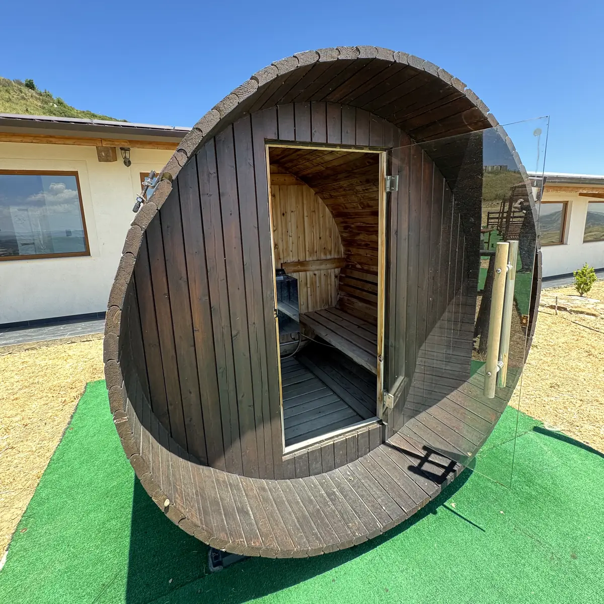 La sauna a botte in legno sul prato, con la porta aperta