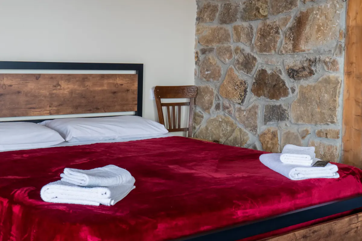 Camera con letto in velluto rosso su parete di pietra
