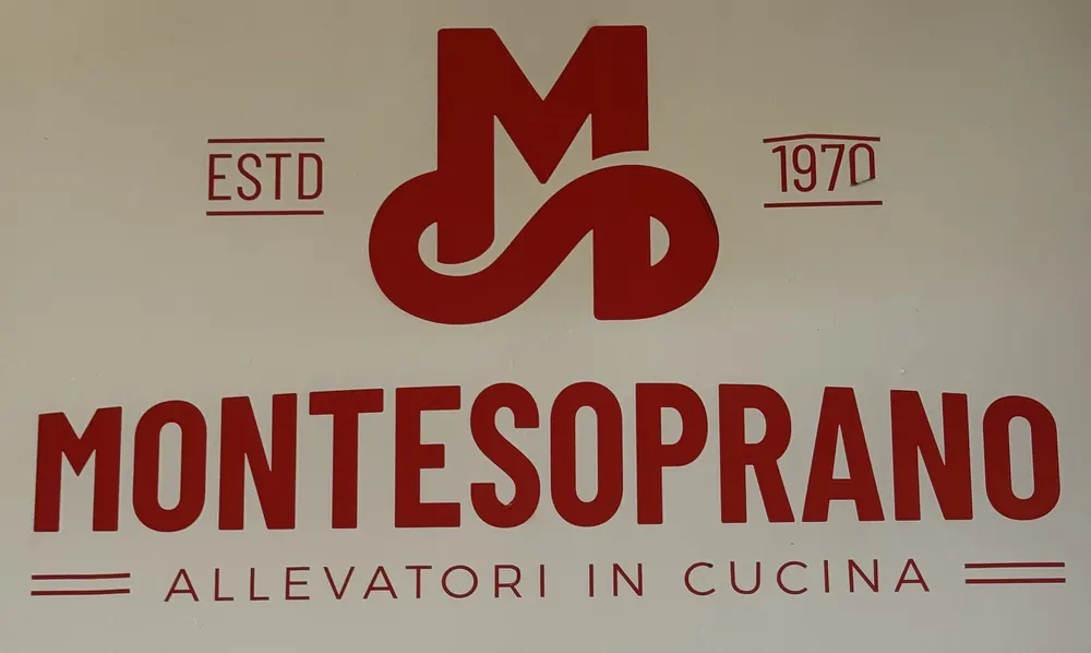 Il marchio MonteSoprano dipinto a parete, con la scritta ESTD 1970 e «Allevatori in cucina»