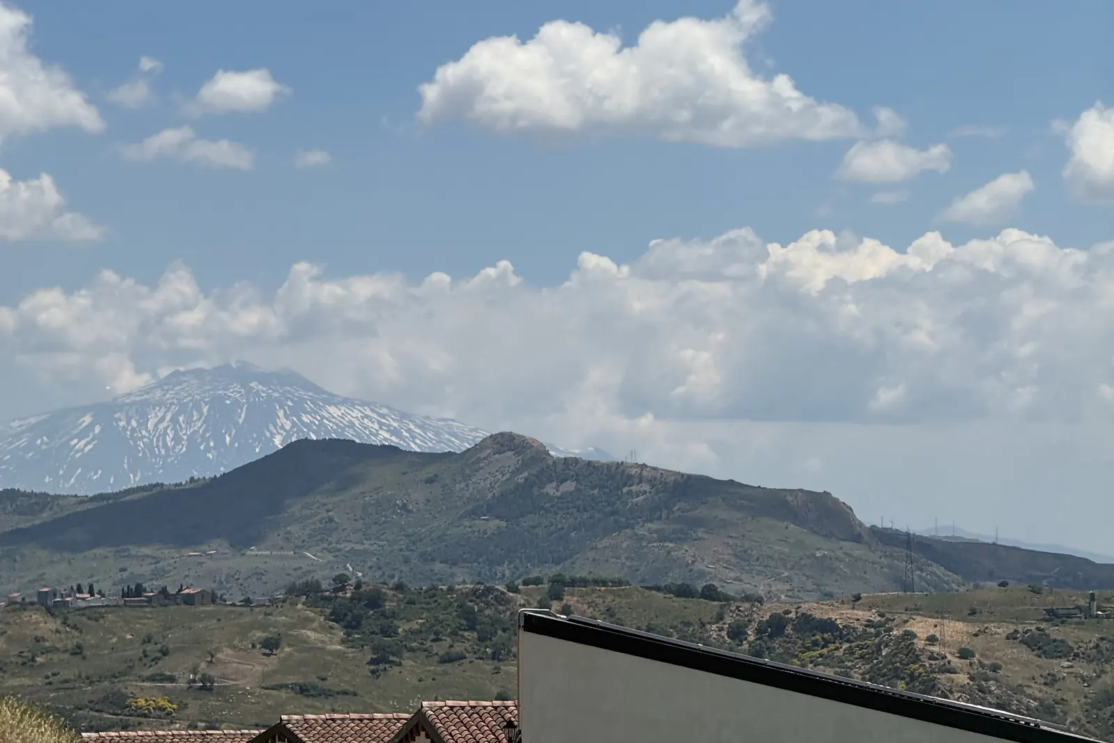 I monti Nebrodi con le nuvole, un bungalow bianco e i lettini dell’agriturismo