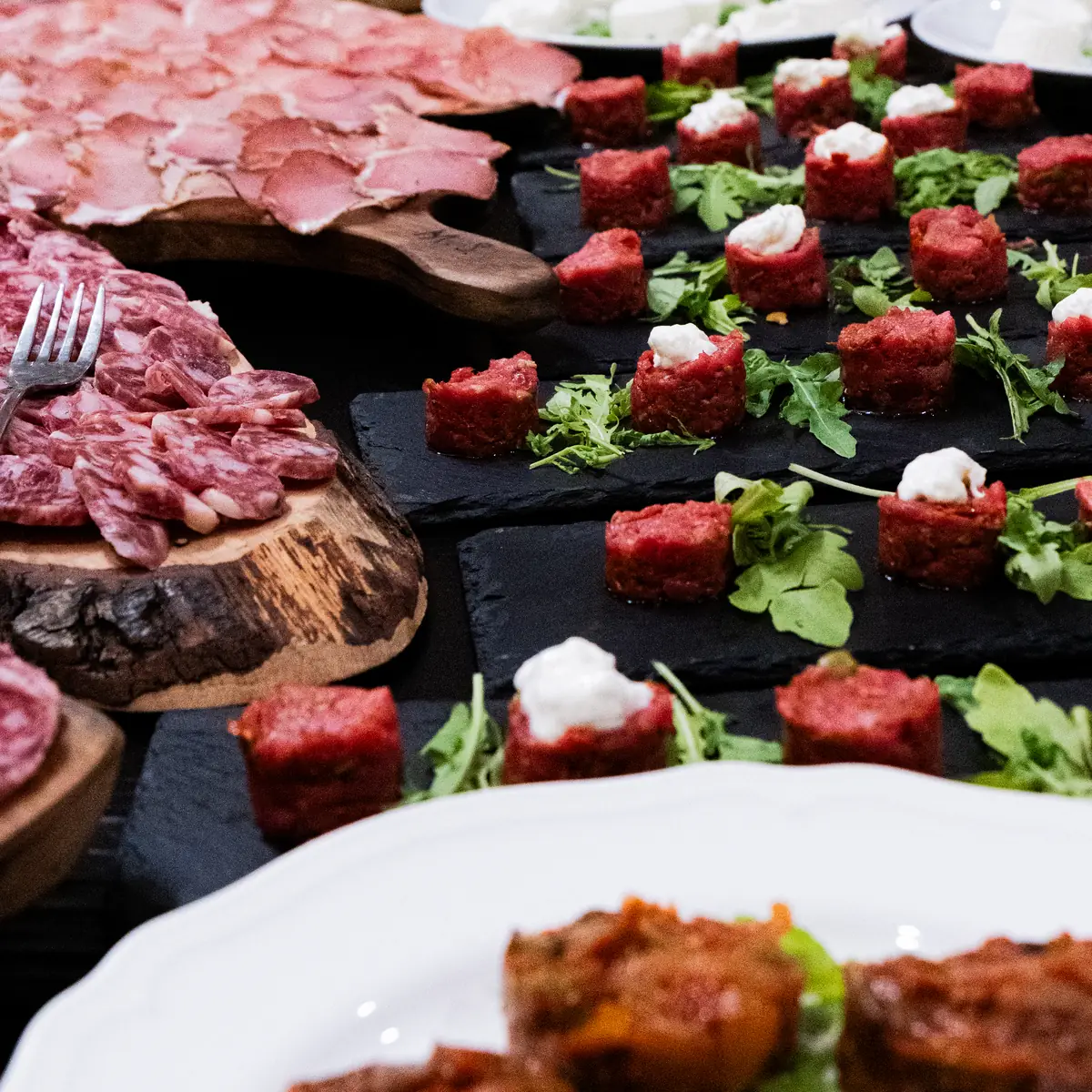 Tartare a cubetti su ardesia e taglieri di salumi sulla tavola