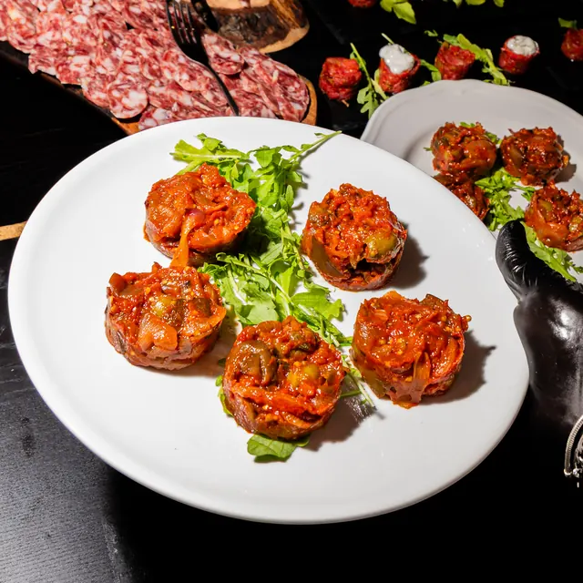Porzioni al sugo su un letto di rucola, in un piatto bianco